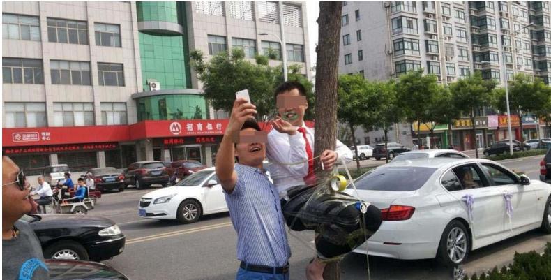 新郎被绑在电线杆上放鞭炮,新郎被绑在电杆上身挂鞭炮